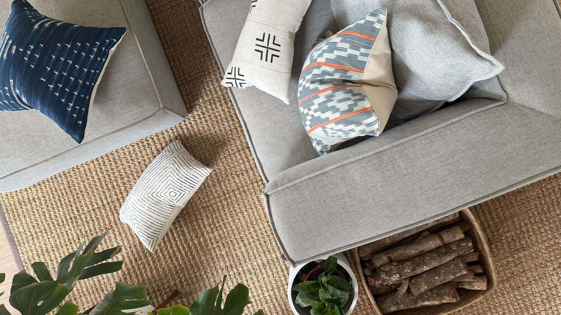 Baule and Mud Cloth scatter cushions on a grey couch.